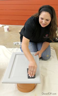 a woman sitting on the ground working on a piece of furniture with a mouse in her hand