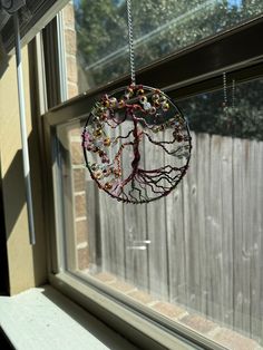 a tree hanging from a window sill in front of a wooden fence with beads on it