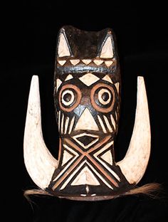 a wooden mask with large horns on it's head and eyes, sitting on a black surface