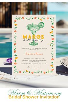 the wedding card is sitting next to a pool