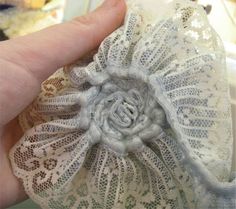 someone is holding an old lace flower in their left hand and it looks like they have been made into something out of fabric