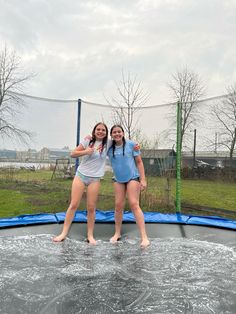 two young women standing on top of a trampoline