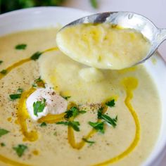 a spoonful of soup with potatoes and parsley on top in a white bowl