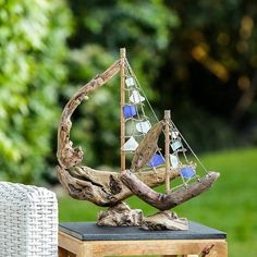 a wooden sailboat sculpture sitting on top of a table next to a white chair