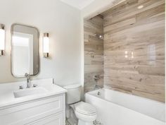 a white bathroom with wooden walls and flooring, along with a toilet and bathtub