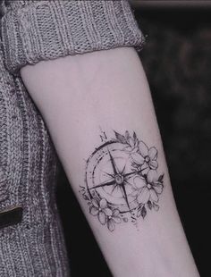 a black and white photo of a compass with flowers on the wrist tattoo design for women