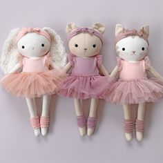 three stuffed animals dressed in pink tutues and ballet shoes hanging on a wall