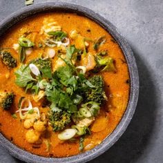 a bowl of soup with broccoli, cauliflower and other vegetables in it