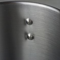 two metal buttons are on the side of a stainless steel object, which appears to be close up