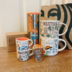 three coffee mugs sitting on top of a table next to a bag and some other items