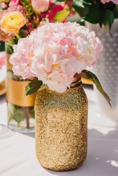 a vase filled with pink flowers on top of a table next to other vases