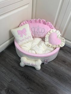 a pink and white dog bed sitting on top of a wooden floor