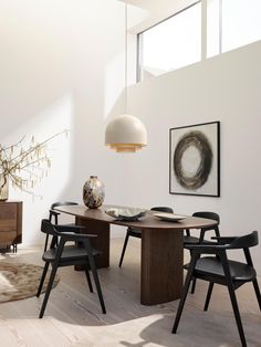 a dining room table with four chairs and a vase on the table next to it