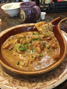 a brown bowl filled with food on top of a table