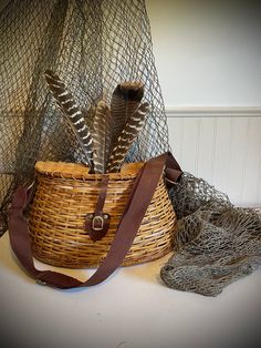 a wicker basket with two feathers in it next to some fishing nets and netting