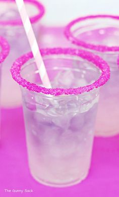 three glasses filled with liquid and pink straws on top of a table next to each other