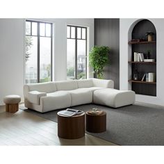 a living room with a large white couch and book shelf in the corner next to a window