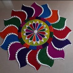 a colorful flower made out of felt on a table top with white beads and bead work