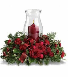 a candle and some red flowers in a vase