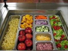 a stainless steel tray filled with lots of different fruits and vegetables next to other foods