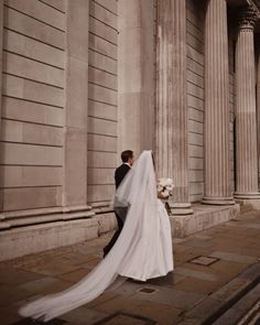 a bride and groom standing in front of an old building with columns on either side