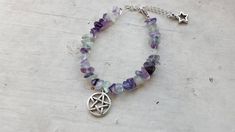 Pentacle Bracelet made with silver toned metal charms and semi precious stones. Pick a crystal. Adjustable chain with a star charm on the end of it. I take custom orders. Amethyst Clear Quartz Black jasper Green Aventurine Rainbow Fluorite Rose Quartz Note: due to the nature of natural chip stones, each piece will be unique. Note: this item is made to order and may take a week to 2 to ship. If you would like a color/crystal not shown, message me and I most likely can get it. Spiritual Silver Amethyst Crystal Bracelet, Spiritual Star-shaped Metal Jewelry, Silver Spiritual Crystal Bracelet, Spiritual Silver Crystal Bracelet, Silver Charm Bracelet With Natural Stones For Healing, Adjustable Silver Crystal Bracelet, Silver Adjustable Crystal Bracelet, Bohemian Silver Amethyst Crystal Bracelet, Black Jasper