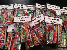 a pile of candy bags filled with different types of gummy bars and white team signs