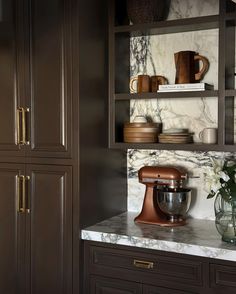 a kitchen with marble counter tops and brown cabinets, including a mixer on the counter