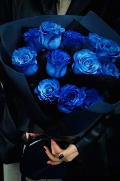 a woman holding a bouquet of blue roses