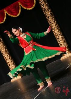 a woman in green and red dress dancing on stage