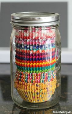 a glass jar filled with lots of colorful crayon pencils on top of a table