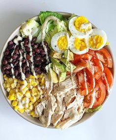 a salad with eggs, tomatoes, black beans, corn, lettuce and dressing