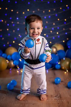 a little boy is holding some blue balls in his hands and smiling at the camera