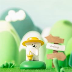 a small toy with a hat on sitting in the grass