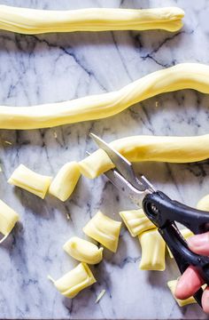 someone is cutting up some food on a marble counter top with a pair of scissors