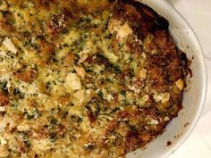 a casserole dish with cheese and other toppings in a white bowl on a table