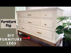 a white dresser sitting on top of a wooden floor next to a potted plant