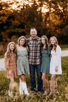 a family posing for a photo in the grass at sunset with trees in the background