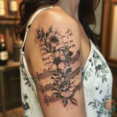 a woman's arm with music notes and flowers on it