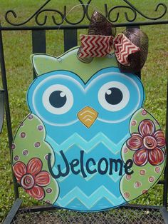 a welcome sign with an owl on it and a bow in the center is decorated with flowers