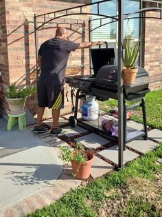 a man standing next to a grill on top of a patio