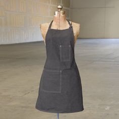 an apron on a mannequin in front of a brick wall and cement floor