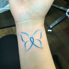 a woman's wrist with a blue ribbon on it and a butterfly tattoo design