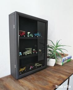 a wooden table topped with toy cars and a potted plant on top of it