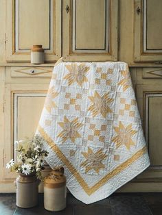 a white and yellow quilt sitting on top of a counter next to two vases