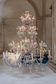 a chandelier in an old building with flowers on the bottom and candles hanging from it