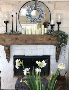 a fireplace with candles and flowers on it