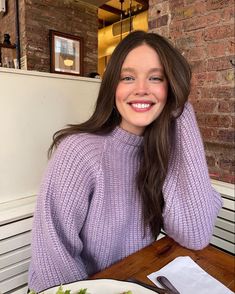 a woman sitting at a table with a plate of food in front of her smiling