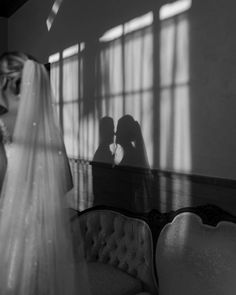 a bride and groom standing in front of a window with their shadow on the wall