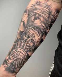 a man's arm with a black and grey tattoo on it, holding his hands together